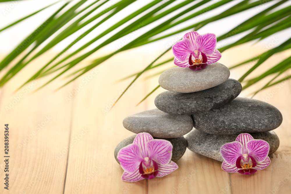Spa stones with orchid flowers on wooden table Spa stones with orchid flowers on wooden table