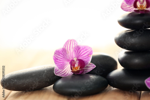 Spa stones with beautiful orchid flowers on wooden table