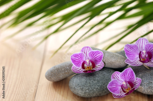 Spa stones with orchid flowers on wooden table