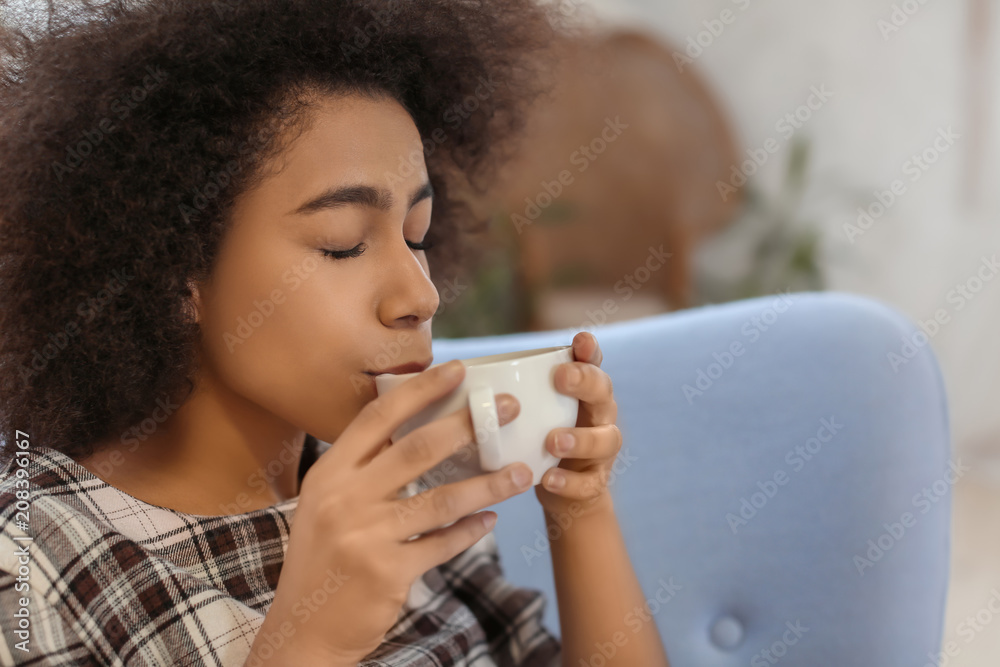 Beautiful African-American woman drinking tea indoors Beautiful African-American woman drinking tea indoors