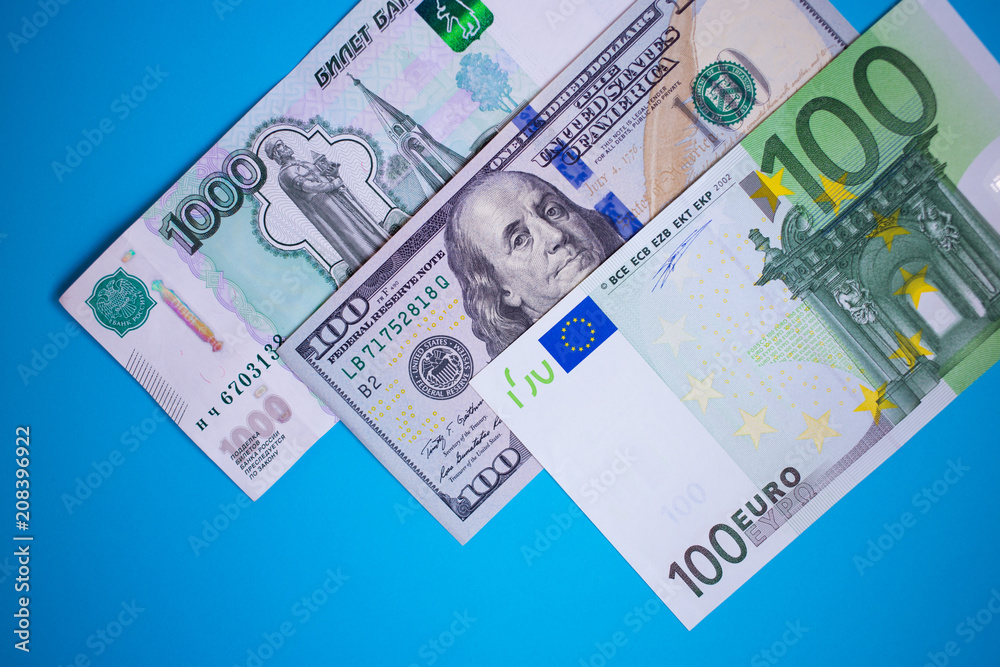 close up bundle of money Euros, dollars, rubles banknotes on the blue background, business, finance, saving, banking concept close up bundle of money Euros, dollars, rubles banknotes on the blue background, business, finance, saving, banking concept