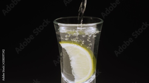 The fruit is poured into the water. Vodka is poured into a glass. Vodka and lime.