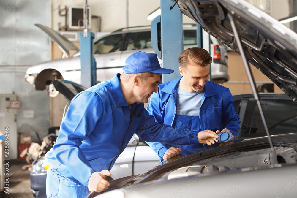 Male mechanics fixing car in service center