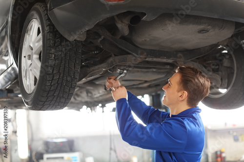 Male mechanic fixing car in...