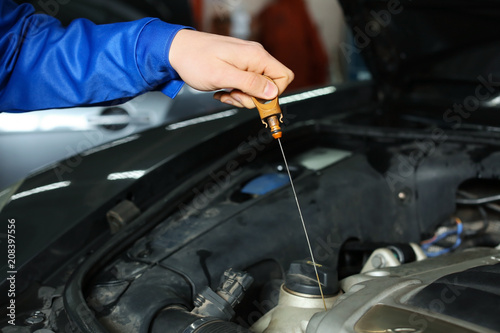Male mechanic checking engine oil level in car service center