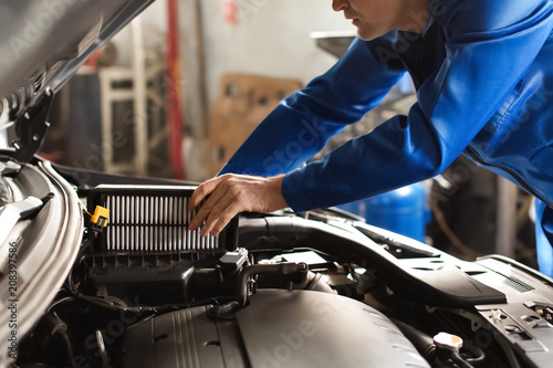 Male mechanic examining car...