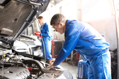 Male mechanic fixing car in...