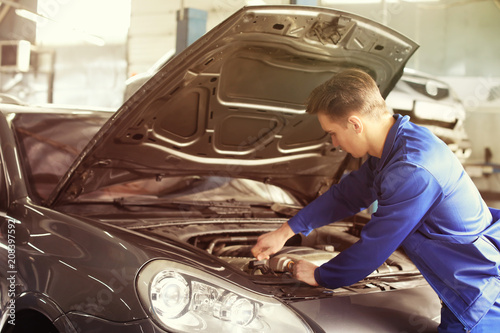 Male mechanic fixing car in...