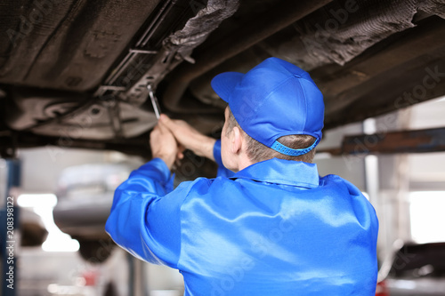 Male mechanic fixing car in...