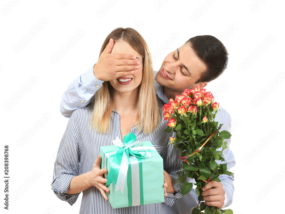Young man giving present and flowers to his beloved girlfriend on white background Young man giving present and flowers to his beloved girlfriend on white background
