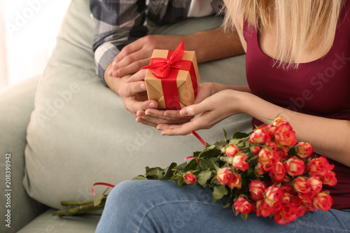 Young man giving present to his beloved girlfriend at home, closeup