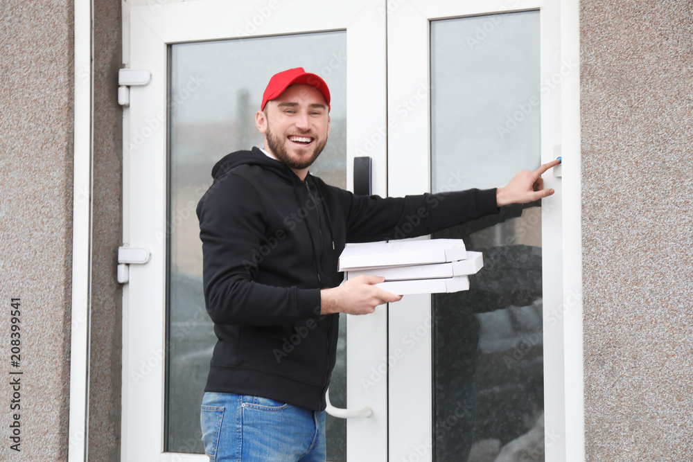 Young man with cardboard pizza boxes ringing doorbell outdoors. Food delivery service Young man with cardboard pizza boxes ringing doorbell outdoors. Food delivery service