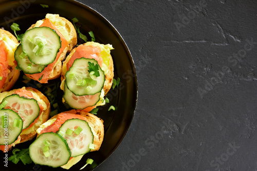 Sandwiches with salmon, scrambled eggs and cucumber