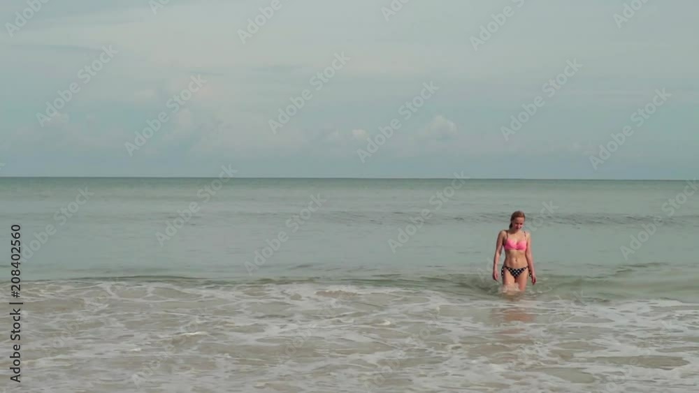Young women in a bikini in a sea with waves enjoys sunbathing and beach vacation Young women in a bikini in a sea with waves enjoys sunbathing and beach vacation
