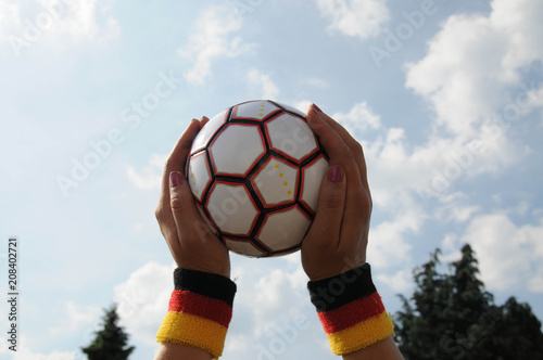 hand mit deutscher fahne hält fußball wm schweißband fanuntensil 2 photo