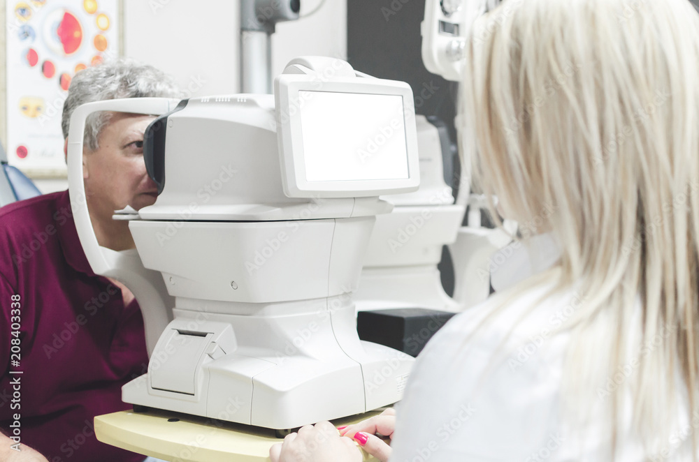 Man looking at refractometer eye test machine in ophthalmology, white empty screen Man looking at refractometer eye test machine in ophthalmology, white empty screen