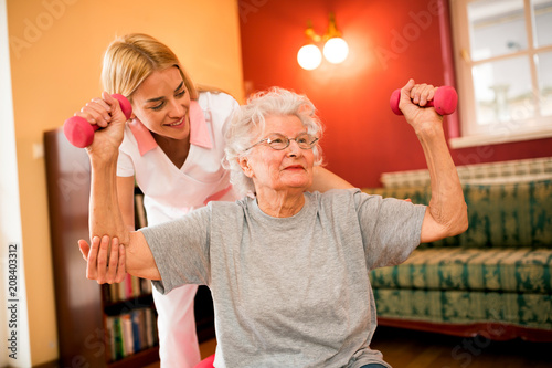 Smilinig positive senior woman enjoy in exercise with nurse photo