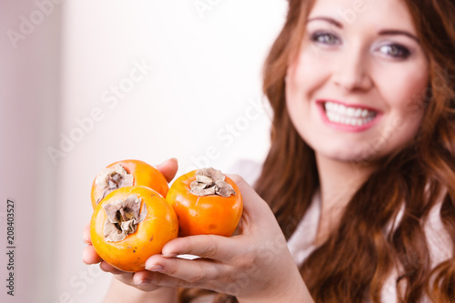 Cheerful woman holds persimmon kaki fruits