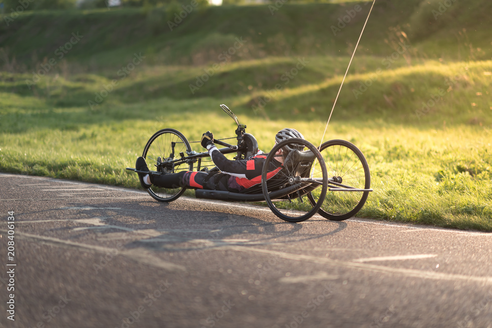 Fototapeta premium A close up of the handbike athlete on the special bicycle asphalt track in Krylatskie Hills. Evening sunset above the road.