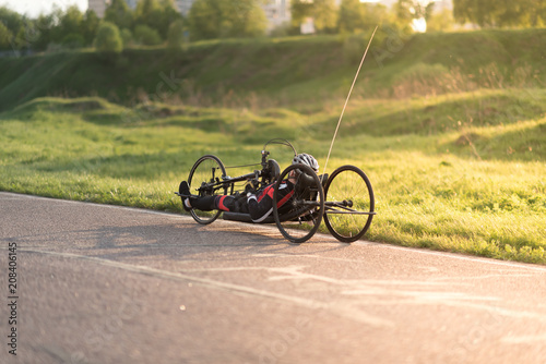 A close up of the handbike athlete on the special bicycle asphalt track in Krylatskie Hills. Evening sunset above the road.