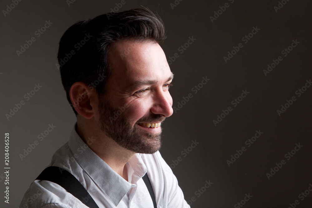 Side of handsome man with beard smiling against gray backgorund