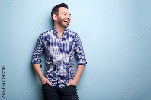cheerful man with beard posing against blue wall © mimagephotos