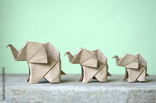 Brown origami elephant on green background