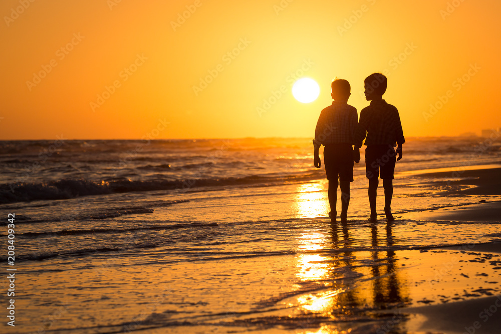 silhouette of boys by the ocean