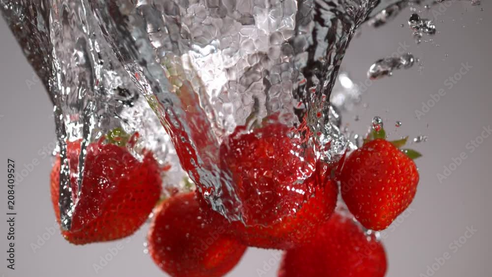 Strawberries falling into water in super slow motion. Shot with high speed cinema camera Phantom VEO, 1000fps.