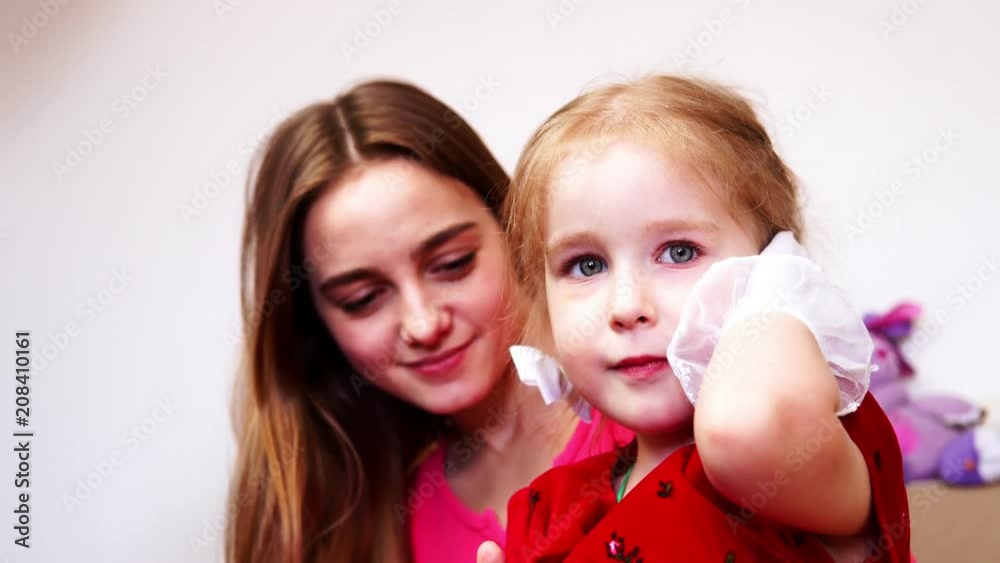 A little girl talking on an imaginary phone. A baby girl holding a sock in her hand. A little girl talking on an imaginary phone. A baby girl holding a sock in her hand.