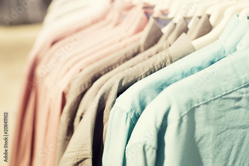 Mens shirts in different colors on hangers in shop, selective focus