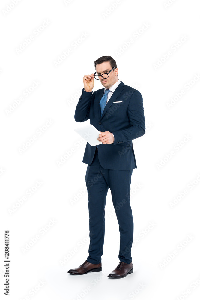 full length view of businessman in eyeglasses holding digital tablet and looking at camera isolated on white full length view of businessman in eyeglasses holding digital tablet and looking at camera isolated on white