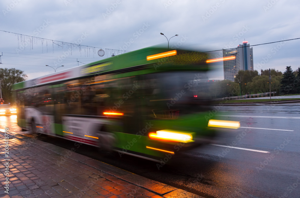 The motion of a blurred bus on the avenue at dusk.