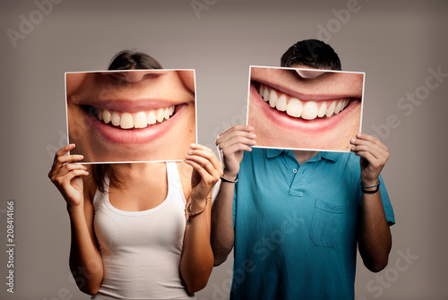 happy couple holding a picture of a mouth smiling on a gray background
