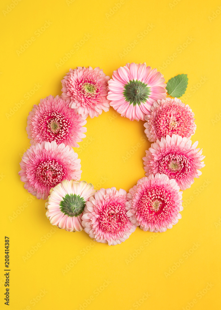 Spring flowers wreath isolated on a yellow background. Gerbera daisy flower petals viewed directly from above. Top view