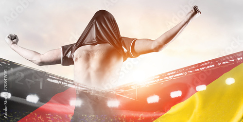 Germany national team. Double exposure photo of stadium and soccer or football player celebrating goal with his jersey on head