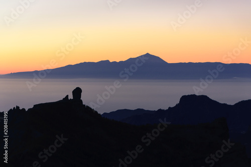 Silhouettes of the mountains of the islands of Gran Canaria and Tenerife. Both islands separated by a sea of       clouds. and a sunset.