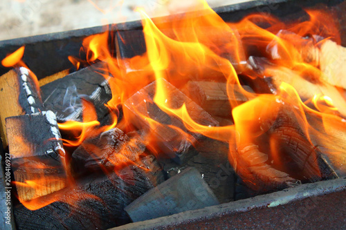 Burning firewood in the grill. Metal brazier. A natural beautiful flame. Close-up. Background.