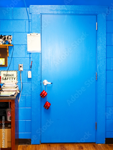 Bright blue door in computer classroom with Think Safety sign and stack of manuals - fuzzy dice hanging from door handle photo