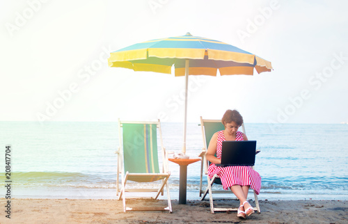 Young woman using laptop computer on a beach. Freelance work concept © Анна Бортникова