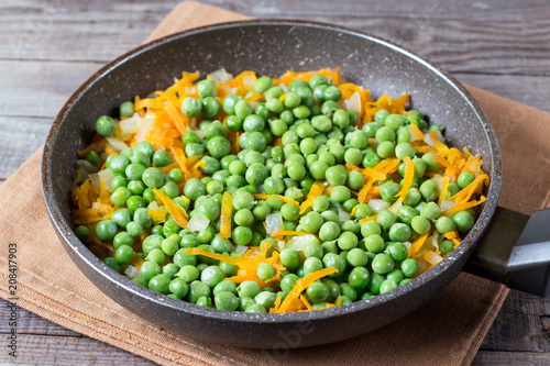 Peas, onions and carrots on a frying pan