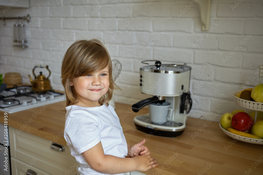Horizontal shot of beautiful four year old baby girl in white casual t-shirt standing at kitchen counter, making coffee and smiling happily, feeling helpful and responsible. Children, kids and cooking Horizontal shot of beautiful four year old baby girl in white casual t-shirt standing at kitchen counter, making coffee and smiling happily, feeling helpful and responsible. Children, kids and cooking