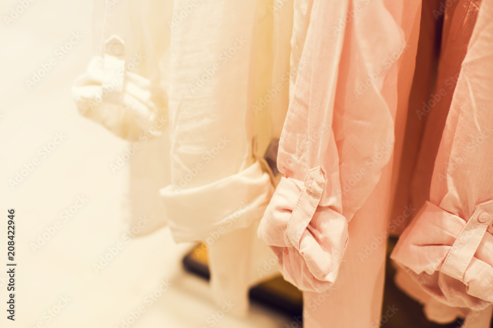 Obraz premium Women's shirts of pastel tones on a hanger in shop, selective focus