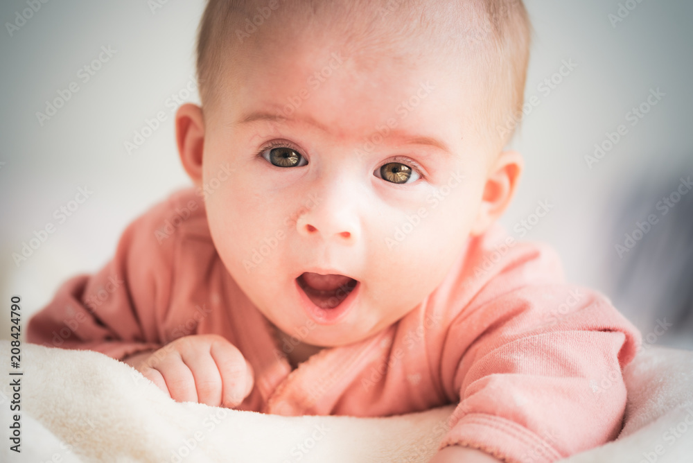 Cute baby girl on bed looking at camera and laughing. Cute baby girl on bed looking at camera and laughing.