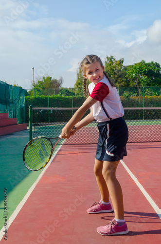 Girl tennis player, playing in the open air. Young girl playing tennis on court © Igor