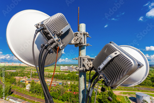 Telecommunication mast with wireless communications systems are including microwave  antennas, fider,  optic and power cables of mobile operators are located on the roof and city landscape as backgrou photo