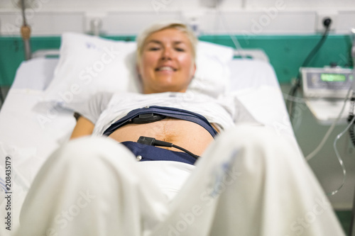 Pregnant woman with ctg laying down on the hospital bed
