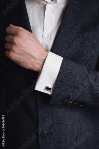 Close-up of a man in a tux fixing his cufflink. groom bow tie cufflinks