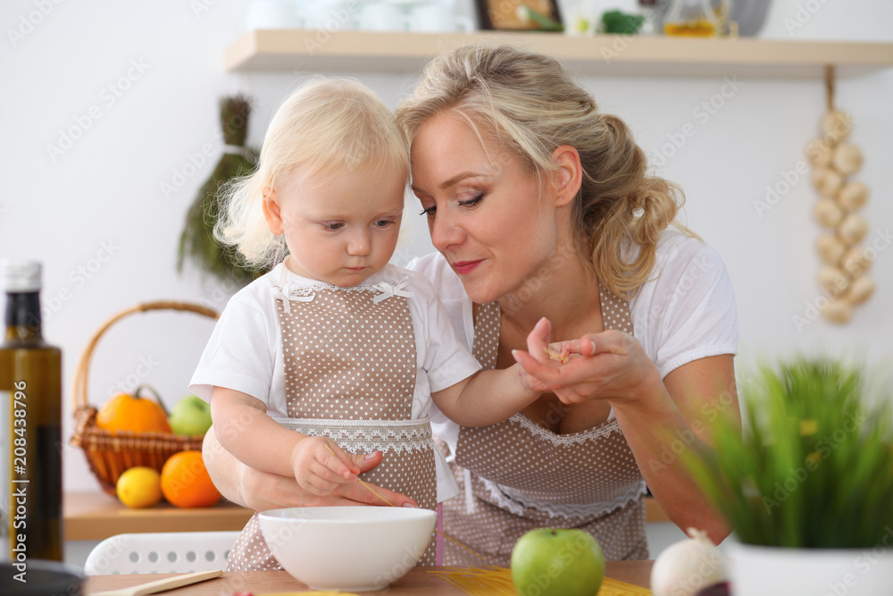 Mother and little daughter cooking in the kitchen. Spending time all together or happy family concept Mother and little daughter cooking in the kitchen. Spending time all together or happy family concept
