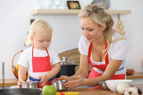 Mother and little daughter cooking in the kitchen. Spending time all together or happy family concept
